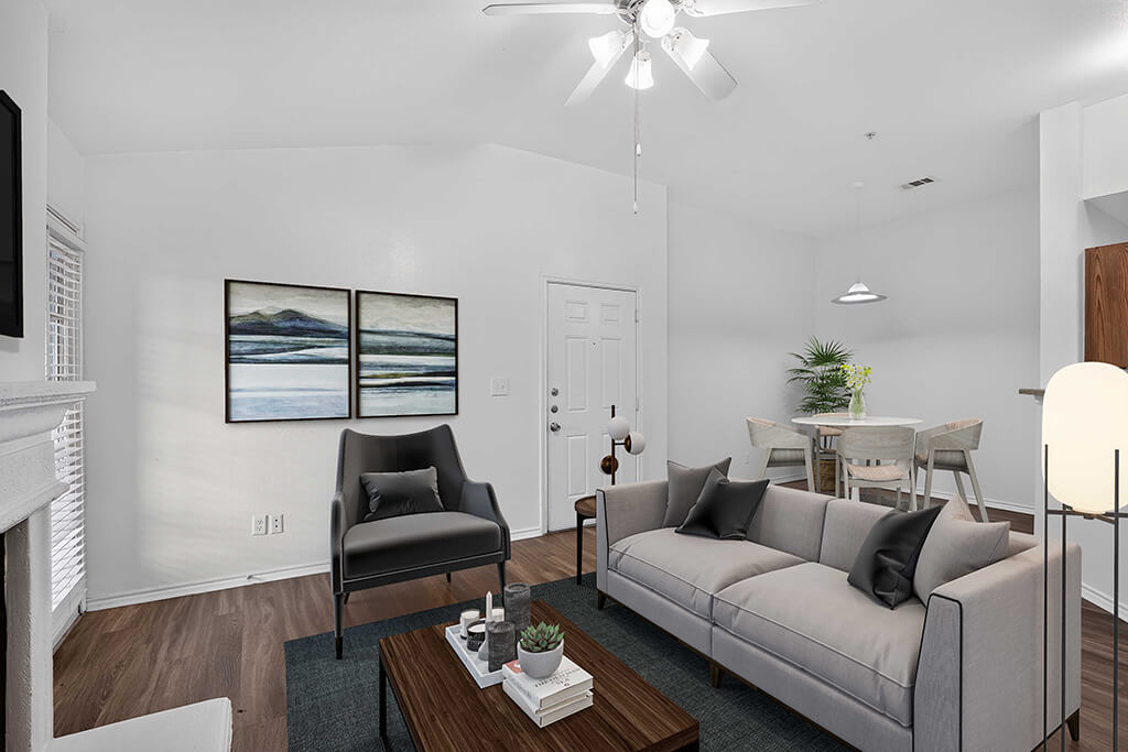 A living room with a grey couch, a black chair, a coffee table, and a painting on the wall.